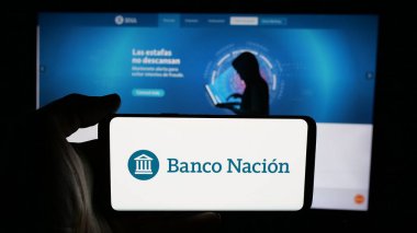 Stuttgart, Almanya - 03-31-2025: Web sayfası önünde ekranda Banco de la Nacion Argentina (BNA) şirketinin logosuyla cep telefonu tutan kişi. Telefon ekranına odaklan.