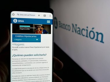 Stuttgart, Almanya - 03-31-2025: Logo önünde ekranda Banco de la Nacion Argentina (BNA) şirketinin web sayfası bulunan kişi. Telefon ekranının merkezine odaklan.