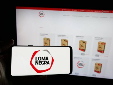 Stuttgart, Almanya - 03-31-2025: Sitenin önünde ekranda Loma Negra Compania Industrial Arjantin S.A. logosu olan akıllı telefon sahibi kişi. Telefon ekranına odaklan.