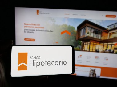 Stuttgart, Almanya - 03-31-2025: Finans şirketi Banco Hipotecario S.A. 'nın logosunu elinde tutan kişi web sitesinin önünde ekranda. Telefon ekranına odaklan.