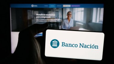 Stuttgart, Almanya - 03-31-2025: İnternet sayfası önünde üzerinde Banco de la Nacion Arjantin (BNA) logosu bulunan cep telefonu sahibi kişi. Telefon ekranına odaklan.