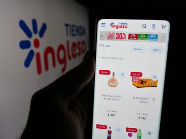 Stuttgart, Almanya - 04-01-2025: Uruguaylı perakende şirketi Tienda Inglesa 'nın web sitesi ile cep telefonu tutan kişi logonun önünde ekranda. Telefon ekranının merkezine odaklan.