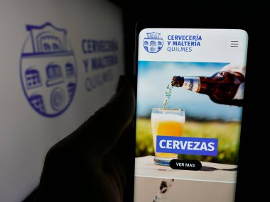 Stuttgart, Almanya - 04-01-2025: Logonun önünde bira üreten Cerveceria y Malteria Quilmes şirketinin logosu olan web sayfası bulunuyor. Telefon ekranının merkezine odaklan.