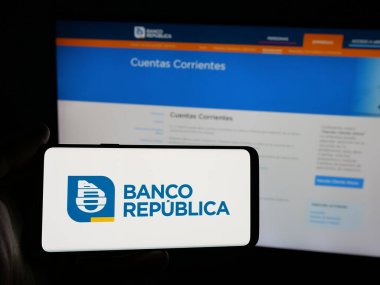 Stuttgart, Almanya - 04-01-2025: Web sitesi önünde ekranda Uruguaylı Banco Republica (BROU) şirketinin logosunu taşıyan kişi görülüyor. Telefon ekranına odaklan.
