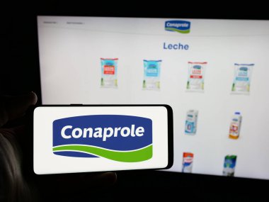 Stuttgart, Almanya - 04-01-2025: Web sitesinin önündeki ekranda Uruguay süt ürünleri kooperatifi Conaprole logosu olan kişi. Telefon ekranına odaklan.