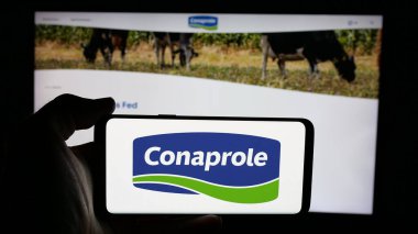Stuttgart, Almanya - 04-01-2025: Web sayfasının önündeki ekranda Uruguay süt ürünleri kooperatifi Conaprole logosu olan kişi. Telefon ekranına odaklan.