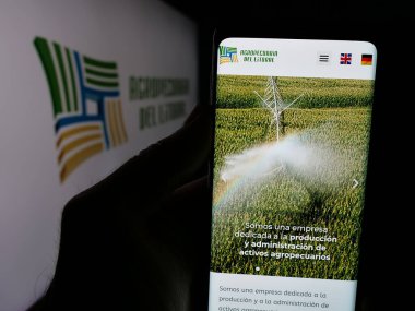 Stuttgart, Almanya - 04-02-2025: Agropecuaria del Litoral S.R.L. şirketinin web sayfası ile cep telefonu tutan kişi Ekranda logonun önünde. Telefon ekranının merkezine odaklan.