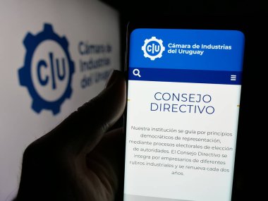 Stuttgart, Almanya - 04-02-2025: Logo önünde ekranda Camara de Industrias del Uruguay adlı organizasyon logosu bulunan kişi. Telefon ekranının merkezine odaklan.