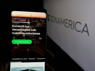 Stuttgart, Almanya - 04-02-2025: Logonun önündeki ekranda iş ve teknoloji parkı Zonamerica logosu logosu bulunan kişi. Telefon ekranının merkezine odaklan.