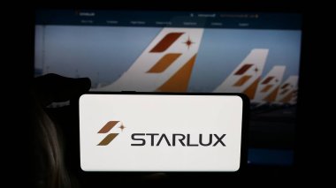 Stuttgart, Almanya - 04-02-2025: Tayvanlı havayolu şirketi Starlux Airlines 'ın logosunun bulunduğu cep telefonu sahibi kişi web sayfasının önünde ekranda. Telefon ekranına odaklan.