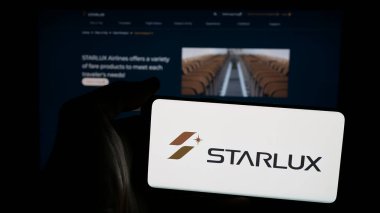 Stuttgart, Almanya - 04-02-2025: Tayvanlı havayolu şirketi Starlux Airlines 'ın logosuna sahip cep telefonu sahibi kişi web sayfasının önünde ekranda. Telefon ekranına odaklan.