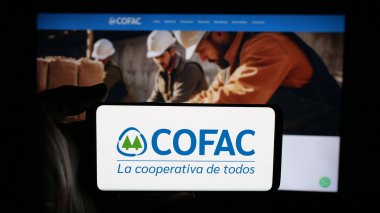 Stuttgart, Almanya - 04-02-2025: Cep telefonunda Uruguaylı mali kooperatif COFAC logosu olan kişi web sayfasının önünde ekranda. Telefon ekranına odaklan.