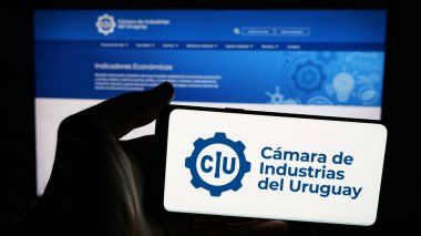 Stuttgart, Almanya - 04-02-2025: İnternet sayfası önünde ekranda Camara de Industrias del Uruguay organizasyonu logosu bulunan cep telefonu sahibi kişi. Telefon ekranına odaklan.
