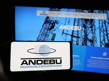 Stuttgart, Almanya - 04-03-2025: Uruguay yayın derneği ANDEBU 'nun logosuna sahip akıllı telefon sahibi kişi web sitesi önünde ekranda. Telefon ekranına odaklan.
