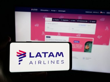 Stuttgart, Almanya - 04-03-2025: Web sitesinin önünde üzerinde havayolu şirketi LATAM Airlines Chile logosu bulunan akıllı telefon sahibi kişi. Telefon ekranına odaklan.