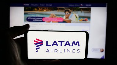 Stuttgart, Almanya - 04-03-2025: Web sayfası önünde havayolu şirketi LATAM Airlines Chile 'in logosuyla cep telefonu tutan kişi. Telefon ekranına odaklan.