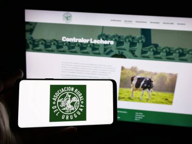 Stuttgart, Almanya - 04-03-2025: Web sitesi önünde üzerinde Asociacion Kırsal del Uruguay (ARU) logosu olan akıllı telefon sahibi kişi. Telefon ekranına odaklan.