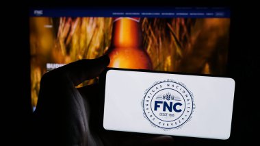 Stuttgart, Almanya - 04-03-2025: İnternet sayfasının önünde Fabricas Nacionales de Cerveza (FNC) şirketinin logosunun bulunduğu cep telefonu sahibi kişi. Telefon ekranına odaklan.