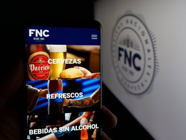 Stuttgart, Almanya - 04-03-2025: Fabricas Nacionales de Cerveza (FNC) şirketinin internet sayfası logonun önünde bulunan kişi. Telefon ekranının merkezine odaklan.