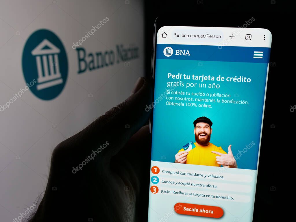 Stuttgart, Germany - 03-31-2025: Person holding web page with logo of company Banco de la Nacion Argentina (BNA) on screen in front of logo. Focus on center of phone display.