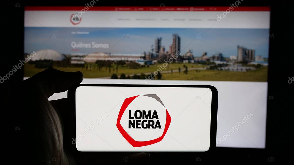 Stuttgart, Germany - 03-31-2025: Person holding cellphone with logo of Loma Negra Compania Industrial Argentina S.A. on screen in front of webpage. Focus on phone display.