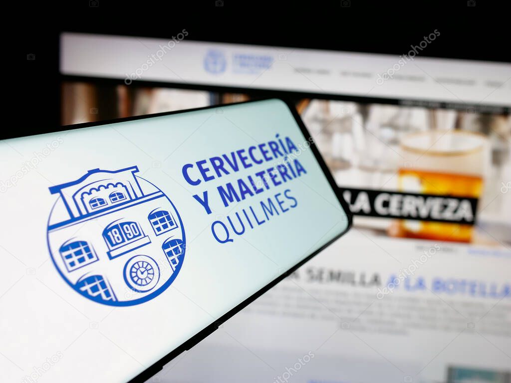 Stuttgart, Germany - 04-01-2025: Smartphone with logo of brewing company Cerveceria y Malteria Quilmes on screen in front of website. Focus on center-left of phone display.