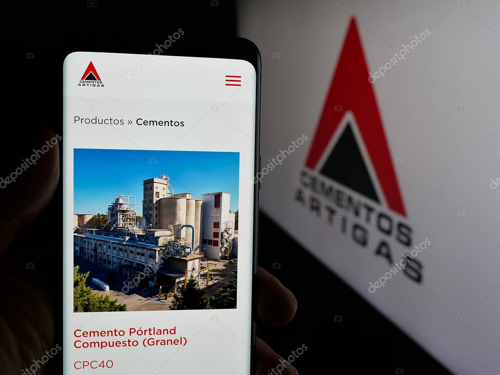 Stuttgart, Germany - 04-02-2025: Person holding cellphone with webpage of Uruguayan company Cementos Artigas S.A. on screen in front of logo. Focus on center of phone display.