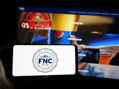 Stuttgart, Almanya - 04-03-2025: İnternet sitesinin önünde Fabricas Nacionales de Cerveza (FNC) şirketinin logosuna sahip akıllı telefon sahibi kişi. Telefon ekranına odaklan.
