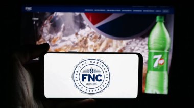 Stuttgart, Almanya - 04-03-2025: İnternet sayfası önünde Fabricas Nacionales de Cerveza (FNC) şirketinin logosunun bulunduğu cep telefonu sahibi kişi. Telefon ekranına odaklan.