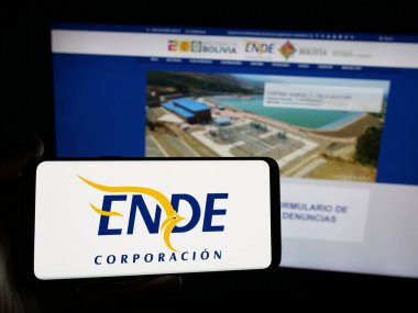 Stuttgart, Almanya - 04-03-2025: Web sitesinin önünde ekranda Empresa Nacional de Electricidad (ENDE) logosunun bulunduğu akıllı telefonu tutan kişi. Telefon ekranına odaklan.