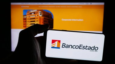 Stuttgart, Almanya - 04-03-2025: Web sayfasının önünde üzerinde Banco del Estado (BancoEstado) logosu olan cep telefonu sahibi kişi. Telefon ekranına odaklan.