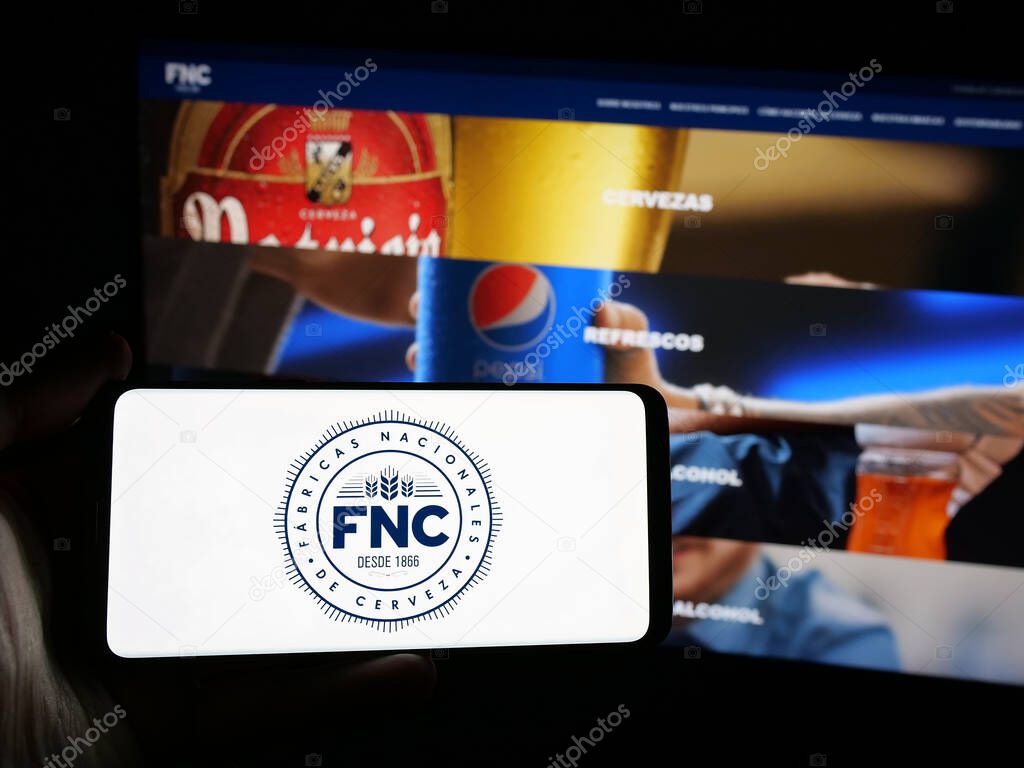 Stuttgart, Germany - 04-03-2025: Person holding smartphone with logo of company Fabricas Nacionales de Cerveza (FNC) on screen in front of website. Focus on phone display.