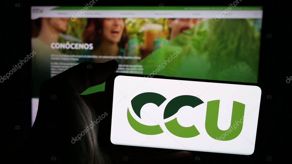 Stuttgart, Germany - 04-03-2025: Person holding mobile phone with logo of Compania Cervecerias Unidas S.A. (CCU) on screen in front of web page. Focus on phone display.