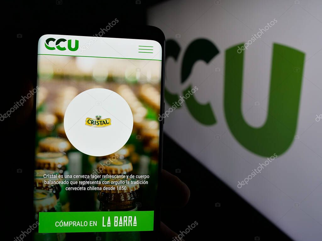 Stuttgart, Germany - 04-03-2025: Person holding cellphone with webpage of Compania Cervecerias Unidas S.A. (CCU) on screen in front of logo. Focus on center of phone display.