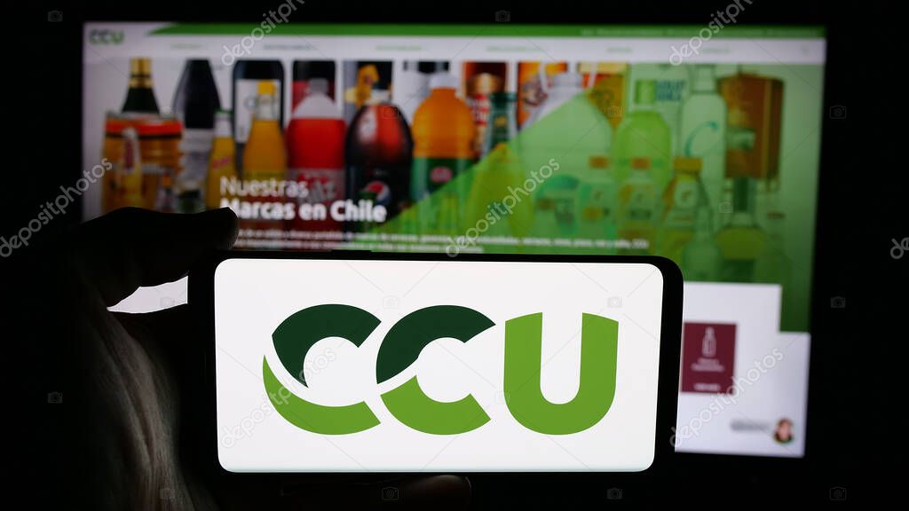 Stuttgart, Germany - 04-03-2025: Person holding cellphone with logo of Compania Cervecerias Unidas S.A. (CCU) on screen in front of webpage. Focus on phone display.