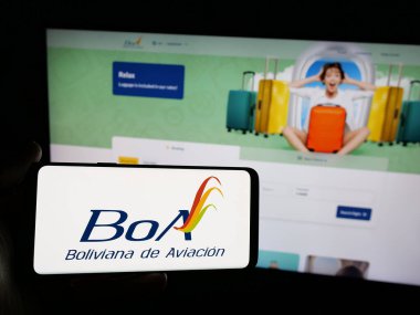 Stuttgart, Almanya - 04-07-2025: İnternet sitesi önünde ekranda Boliviana de Aviacion (BoA) havayolu şirketinin logosunun bulunduğu akıllı telefon sahibi kişi. Telefon ekranına odaklan.