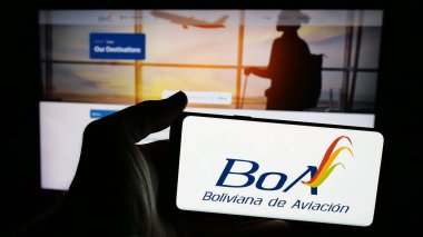 Stuttgart, Almanya - 04-07-2025: Web sayfası önünde ekranda Boliviana de Aviacion (BoA) havayolu şirketinin logosunun bulunduğu cep telefonu sahibi kişi. Telefon ekranına odaklan.