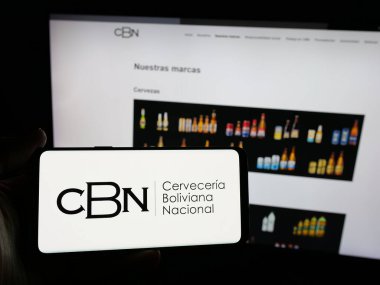 Stuttgart, Almanya - 04-07-2025: İnternet sitesinin önünde üzerinde Cerveceria Boliviana Nacional (CBN) şirketinin logosu bulunan akıllı telefon sahibi kişi. Telefon ekranına odaklan.