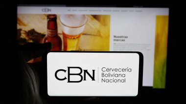 Stuttgart, Almanya - 04-07-2025: İnternet sayfası önünde Cerveceria Boliviana Nacional (CBN) şirketinin logosuna sahip cep telefonu sahibi kişi. Telefon ekranına odaklan.