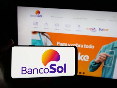 Stuttgart, Almanya - 04-07-2025: İnternet sitesi önünde Banco Solidario S.A. (BancoSol) şirketinin logosuna sahip akıllı telefonu elinde tutan kişi. Telefon ekranına odaklan.