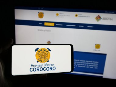 Stuttgart, Almanya - 04-07-2025: Web sitesinin önünde ekranda Empresa Minera Corocoro (COMIBOL) şirketinin logosuna sahip akıllı telefon sahibi kişi görülüyor. Telefon ekranına odaklan.