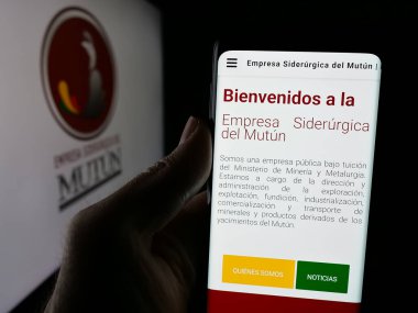 Stuttgart, Almanya - 04-07-2025: Logo önünde ekranda Empresa Siderurgica del Mutun (ESM) şirketinin web sayfası bulunan kişi. Telefon ekranının merkezine odaklan.