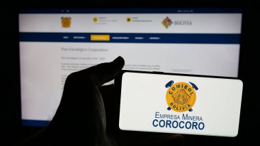 Stuttgart, Almanya - 04-07-2025: Web sayfasının önünde ekranda Empresa Minera Corocoro (COMIBOL) şirketinin logosunun bulunduğu cep telefonu sahibi kişi. Telefon ekranına odaklan.