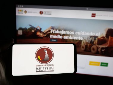 Stuttgart, Almanya - 04-07-2025: Web sitesi önünde ekranda Empresa Siderurgica del Mutun (ESM) şirketinin logosuna sahip akıllı telefon sahibi kişi görülüyor. Telefon ekranına odaklan.