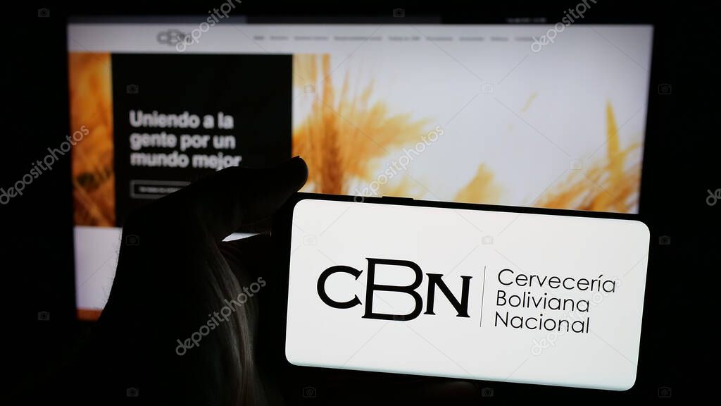 Stuttgart, Germany - 04-07-2025: Person holding mobile phone with logo of company Cerveceria Boliviana Nacional (CBN) on screen in front of web page. Focus on phone display.