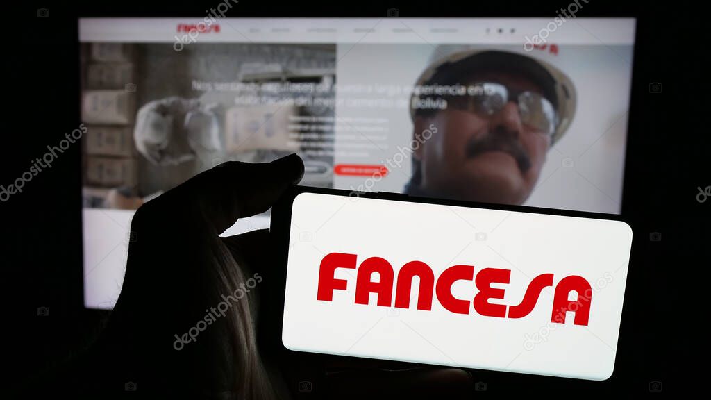 Stuttgart, Germany - 04-09-2025: Person holding mobile phone with logo of company Fabrica Nacional de Cemento (FANCESA) on screen in front of web page. Focus on phone display.