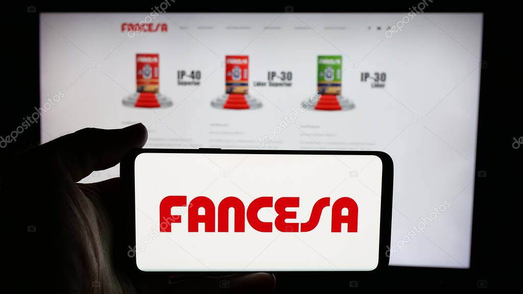 Stuttgart, Germany - 04-09-2025: Person holding cellphone with logo of company Fabrica Nacional de Cemento (FANCESA) on screen in front of webpage. Focus on phone display.