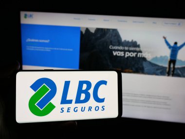 Stuttgart, Almanya - 04-09-2025: Bolivyalı sigorta şirketi LBC Seguros 'un logosuna sahip akıllı telefon sahibi kişi web sitesinin önünde ekranda. Telefon ekranına odaklan.