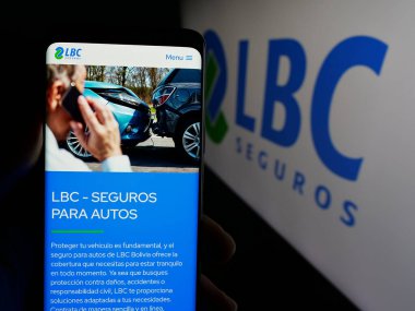 Stuttgart, Almanya - 04-09-2025: Bolivyalı sigorta şirketi LBC Seguros 'un web sitesi ile logo önünde akıllı telefon tutan kişi. Telefon ekranının merkezine odaklan.