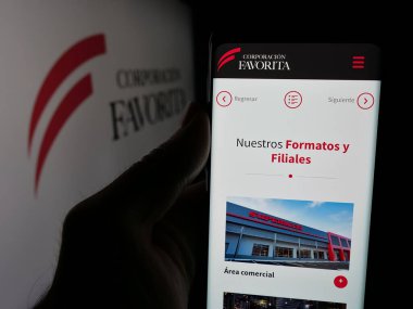 Stuttgart, Almanya - 04-09-2025: Perakende şirketi Corporacion Favorita C.A. web sayfası ile cep telefonu tutan kişi Ekranda logonun önünde. Telefon ekranının merkezine odaklan.
